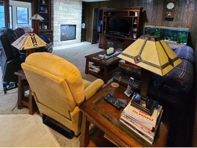 living room with wood walls, a fireplace, and carpet flooring