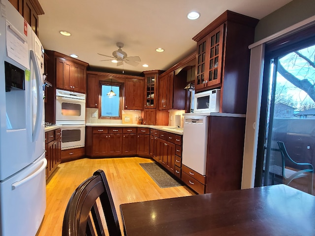 kitchen featuring ceiling fan, white appliances, light wood-type flooring, and hanging light fixtures