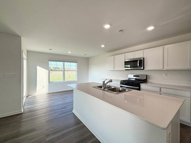 kitchen with appliances with stainless steel finishes, white cabinetry, sink, dark wood-type flooring, and a center island with sink