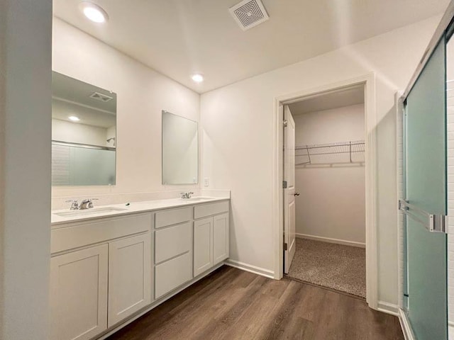 bathroom with hardwood / wood-style floors, walk in shower, and vanity