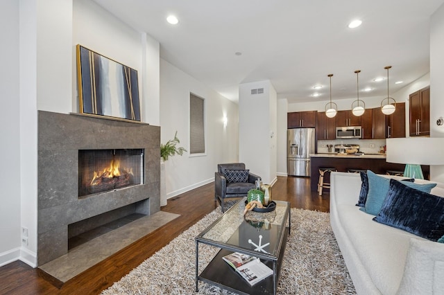 living room with a tile fireplace and dark hardwood / wood-style flooring