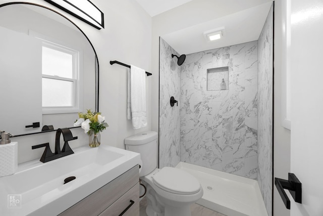 bathroom with toilet, vanity, and a tile shower