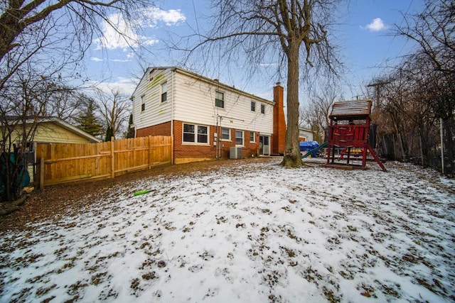 snow covered house featuring central AC unit and a playground