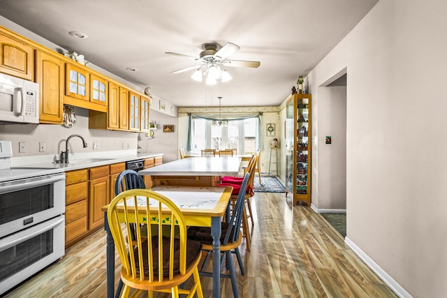 kitchen with a kitchen island, sink, light wood-type flooring, ceiling fan, and white appliances