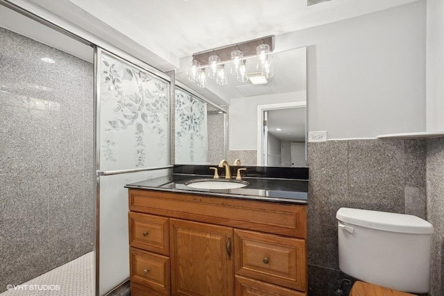 bathroom with vanity, toilet, tile walls, and a shower with door