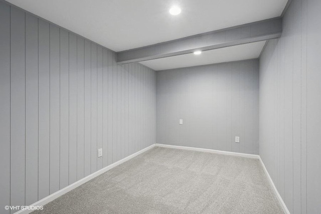 carpeted empty room with beam ceiling and wooden walls