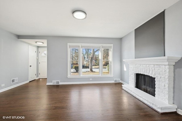 unfurnished living room featuring a brick fireplace and dark hardwood / wood-style flooring