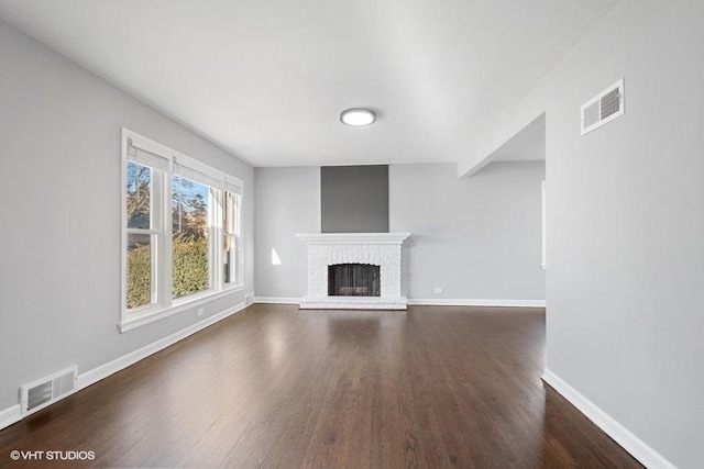 unfurnished living room featuring a brick fireplace and dark hardwood / wood-style flooring