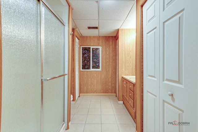 bathroom featuring vanity, a paneled ceiling, wooden walls, and a shower with shower door