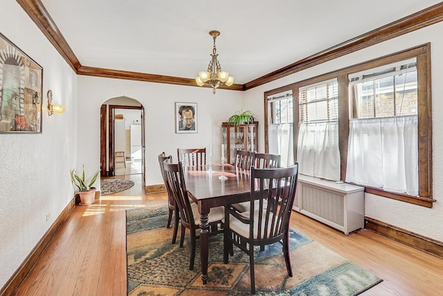 dining room featuring hardwood / wood-style floors, crown molding, radiator heating unit, and a chandelier