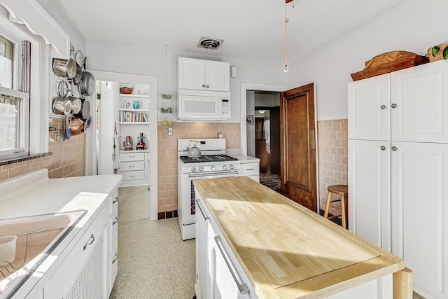 kitchen with white cabinetry, sink, white appliances, and tile walls