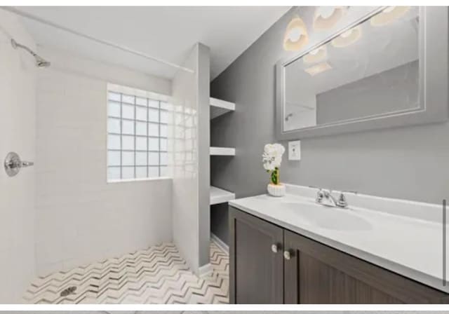 bathroom with a tile shower and vanity