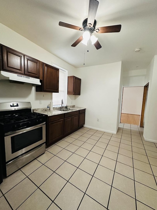 kitchen with light tile patterned flooring, ceiling fan, dark brown cabinetry, and stainless steel gas stove