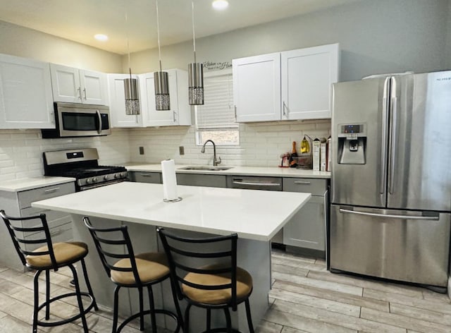 kitchen with sink, a breakfast bar, appliances with stainless steel finishes, a center island, and white cabinets