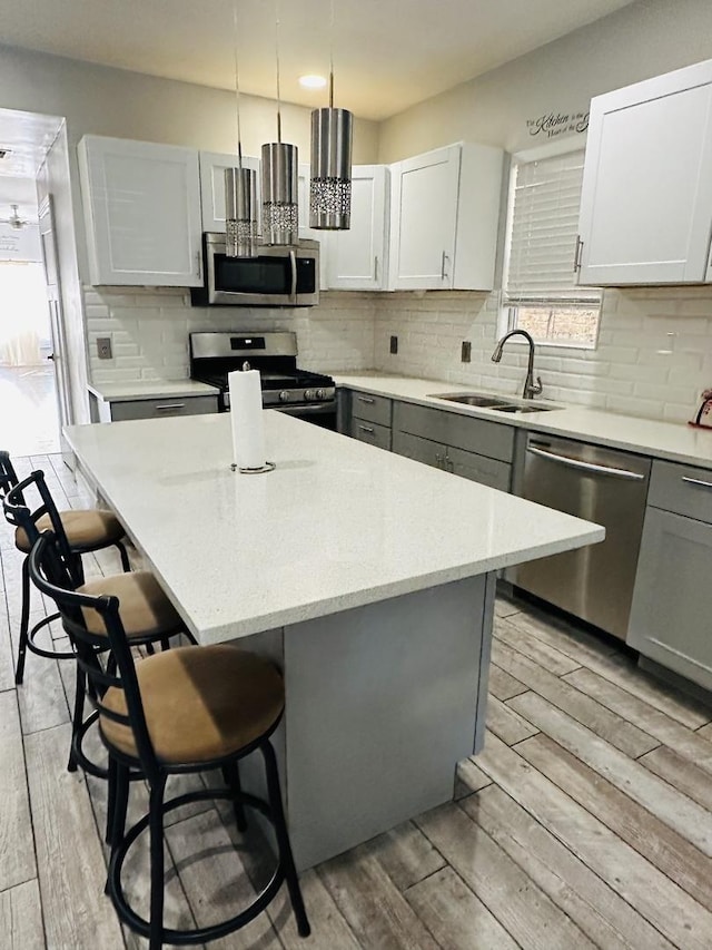 kitchen featuring a kitchen bar, sink, a center island, hanging light fixtures, and appliances with stainless steel finishes