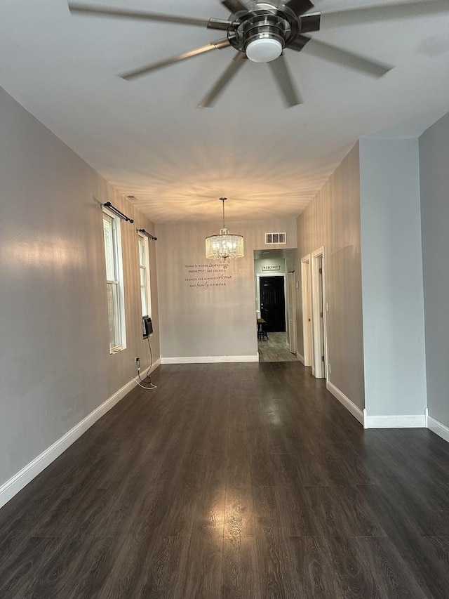 unfurnished living room with dark wood-type flooring and ceiling fan with notable chandelier