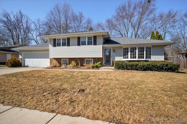 split level home with an attached garage, concrete driveway, a front yard, and fence