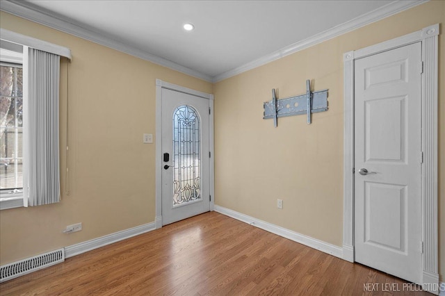 entryway with crown molding, wood finished floors, visible vents, and baseboards