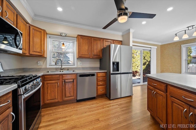 kitchen featuring a sink, appliances with stainless steel finishes, ornamental molding, and brown cabinetry