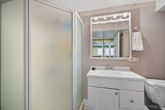 bathroom with a stall shower, toilet, and vanity