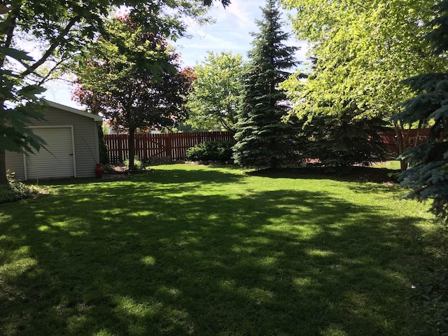 view of yard featuring an outdoor structure, a shed, and fence