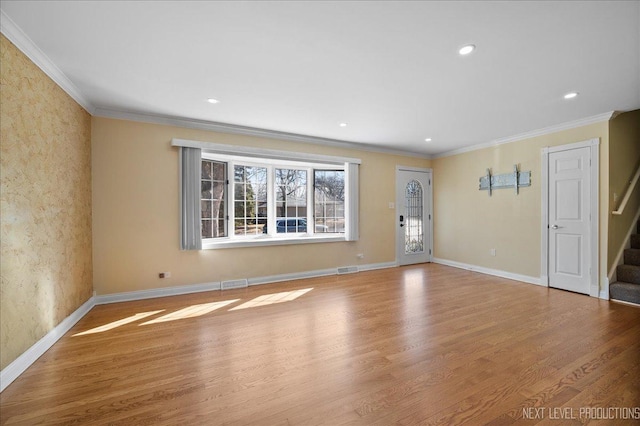 empty room featuring baseboards, wood finished floors, and stairs