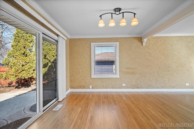 empty room with visible vents, wood finished floors, baseboards, and ornamental molding