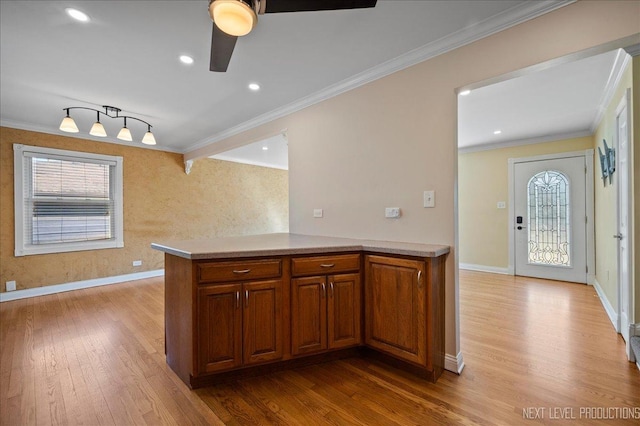 kitchen with crown molding, brown cabinetry, light wood-type flooring, and baseboards