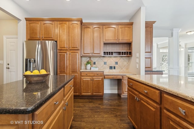 kitchen featuring dark stone counters, dark hardwood / wood-style floors, stainless steel fridge with ice dispenser, and ornate columns