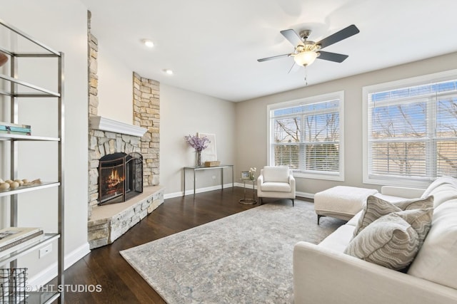 living room with dark hardwood / wood-style floors, ceiling fan, and a stone fireplace