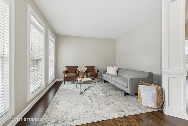 living room featuring decorative columns and dark wood-type flooring