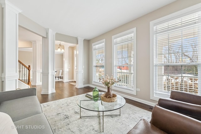 living room featuring an inviting chandelier, dark hardwood / wood-style flooring, and ornate columns