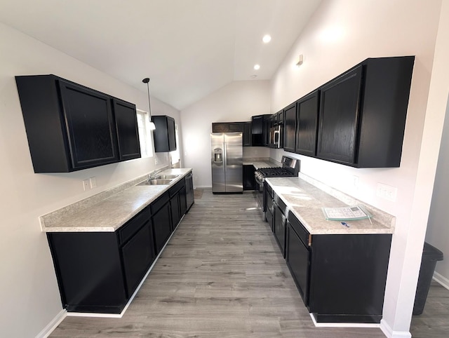 kitchen featuring light hardwood / wood-style floors, stainless steel appliances, vaulted ceiling, pendant lighting, and sink