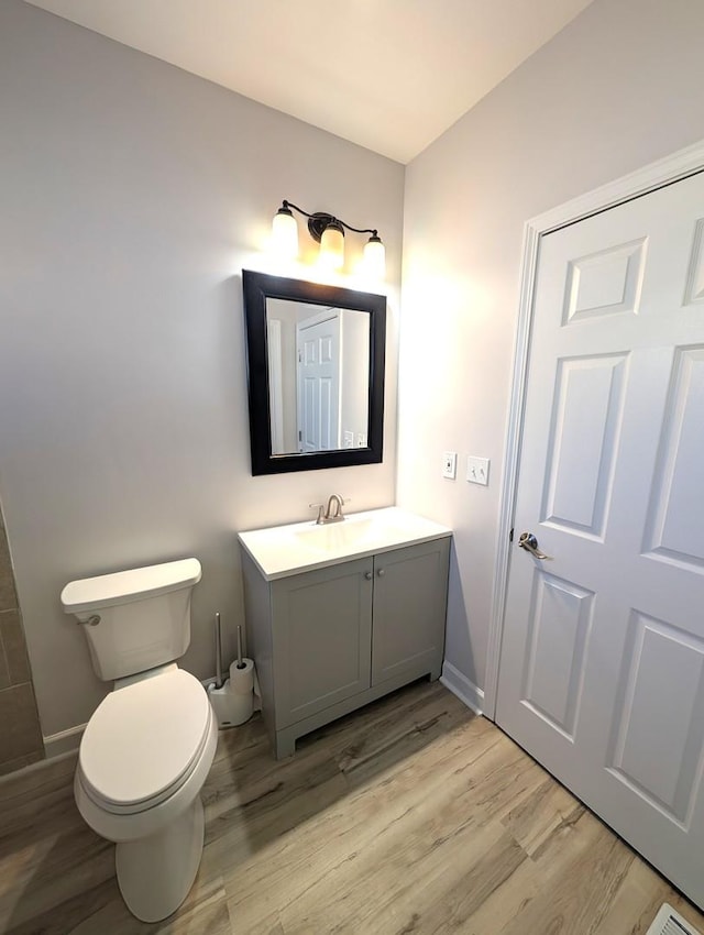 bathroom with toilet, vanity, and hardwood / wood-style flooring