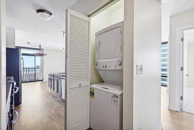 laundry room featuring stacked washer and clothes dryer and light hardwood / wood-style floors