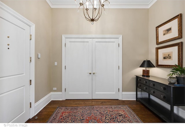 foyer entrance with an inviting chandelier, ornamental molding, and dark hardwood / wood-style floors