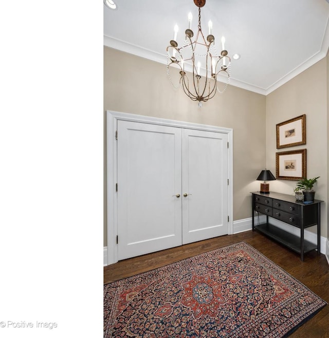 entryway with crown molding, dark hardwood / wood-style floors, and a notable chandelier