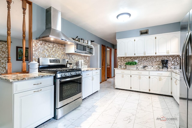 kitchen featuring white cabinetry, decorative backsplash, range hood, and appliances with stainless steel finishes