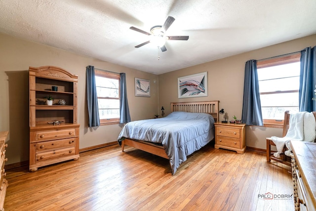 bedroom with ceiling fan, light hardwood / wood-style flooring, and a textured ceiling