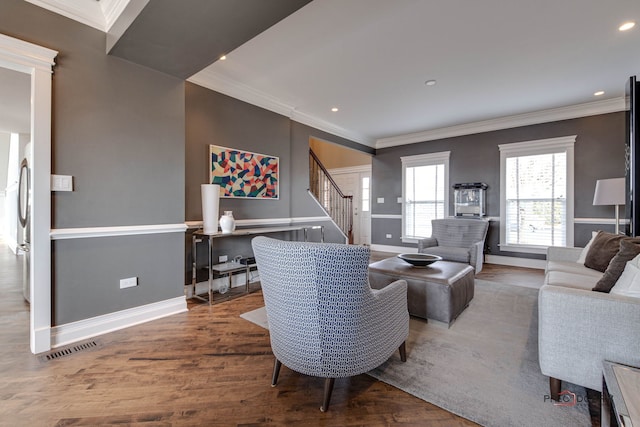 living area with ornamental molding, wood finished floors, visible vents, and stairs