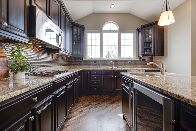 kitchen with wine cooler, light stone counters, stainless steel appliances, and a sink