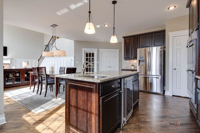 kitchen featuring beverage cooler, dark wood-style flooring, stainless steel appliances, and a sink