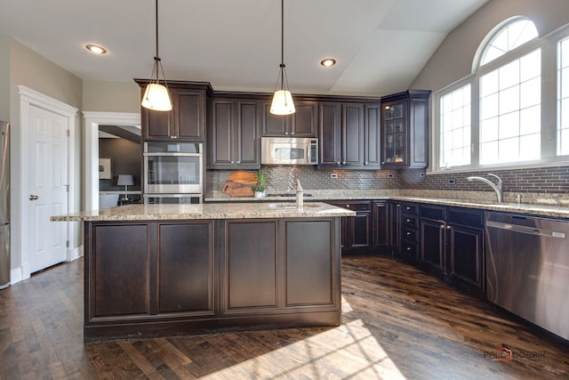 kitchen with dark wood-style flooring, a sink, dark brown cabinets, appliances with stainless steel finishes, and an island with sink