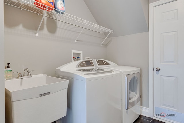 clothes washing area with laundry area, dark tile patterned flooring, a sink, and washing machine and clothes dryer