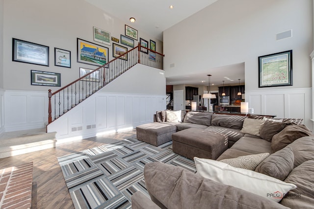 living room with wood finished floors, visible vents, a decorative wall, and stairs