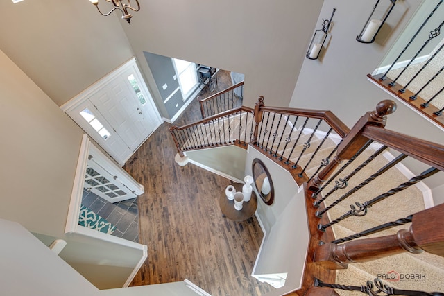 staircase featuring a notable chandelier, baseboards, and wood finished floors