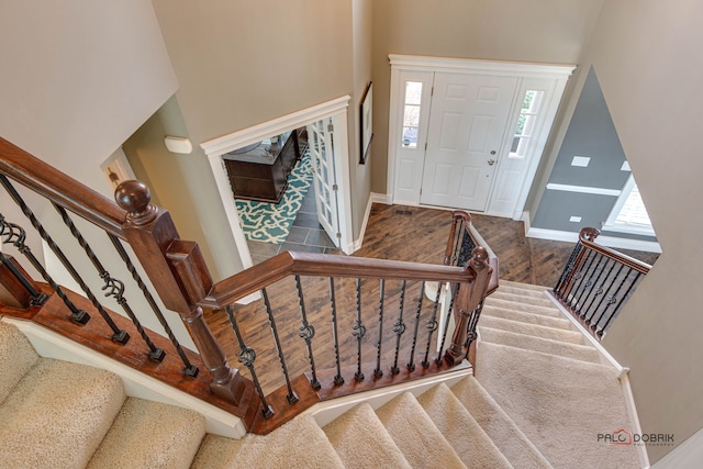 entryway featuring a towering ceiling, stairway, baseboards, and wood finished floors