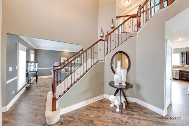 staircase featuring a high ceiling, wood finished floors, and baseboards