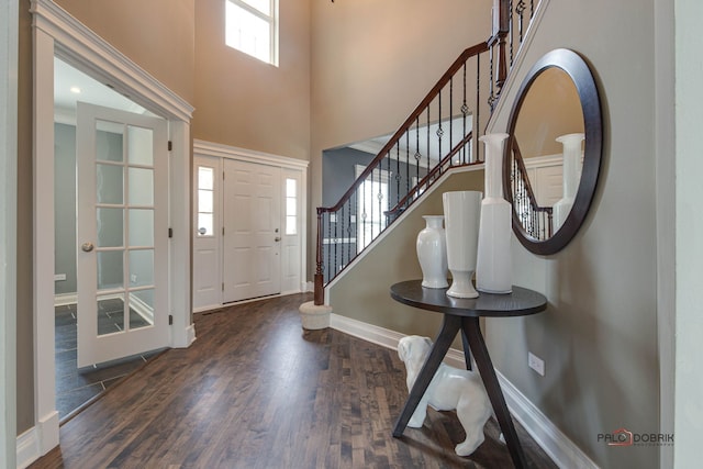 entryway featuring stairs, a towering ceiling, baseboards, and wood finished floors