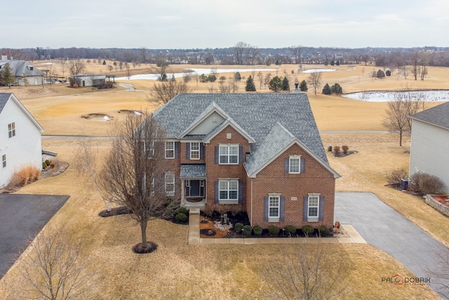 view of front of property with driveway, brick siding, and roof with shingles